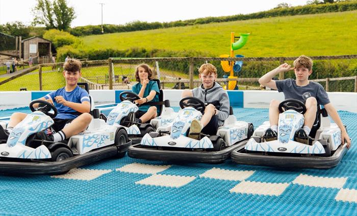 Four boys on the Skiddy cars smiling and ready to start their race!